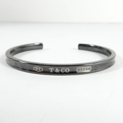 un gros plan sur un bracelet manchette noir portant l'inscription « t & co »