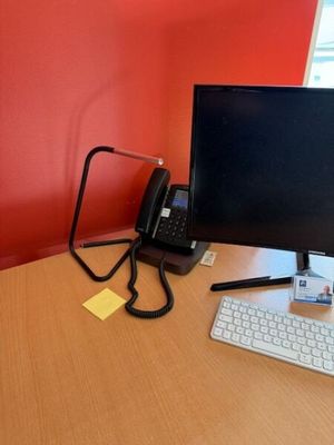 a computer monitor and keyboard on a desk in front of a red wall