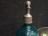a blue glass bottle sitting on a table next to a glass cup