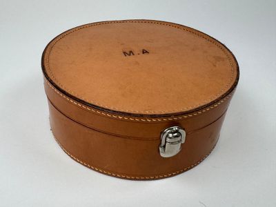une petite boîte ronde munie d'une poignée, posée sur une surface blanche