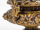 a gold and black vase sitting on a wooden stand