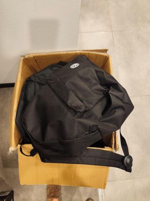 une personne debout à côté d'une boîte sur laquelle est posé un sac à dos