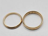 two gold wedding rings on a white surface
