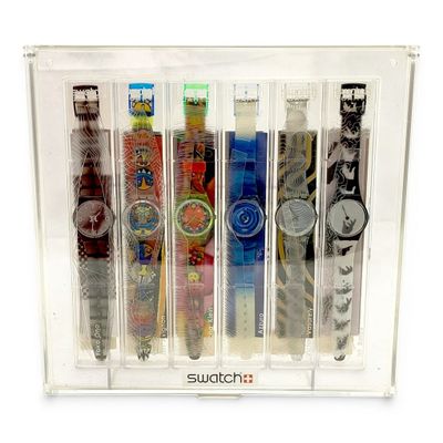 five watches in a clear display case on a white background