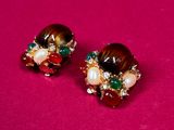 pair of brown and green earrings with pearls on a pink surface