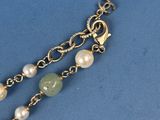 a close up of a gold chain bracelet with pearls on it