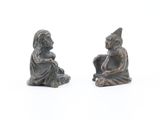 two figurines of a man and a woman sitting on the ground
