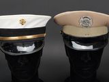 pair of military hats on mannequin heads on a black background