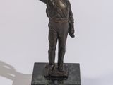 une statue en bronze représentant un homme tenant un pistolet