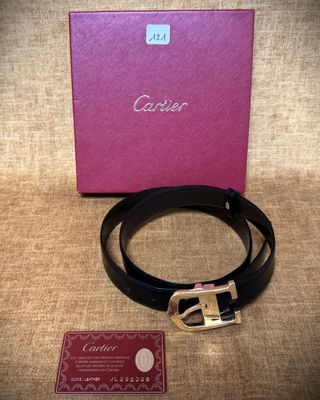 une ceinture noire avec une boucle dorée et une boîte rose