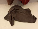 a bed with a brown blanket on it next to a red curtain