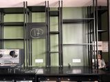 une étagère noire sur laquelle est posée une horloge, dans une pièce