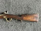 an old rifle laying on the ground with a wooden handle