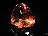 an orange diamond on a black surface with a black background