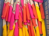 de nombreux couteaux de différentes couleurs dans un panier en plastique