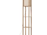 Le lampadaire est en bois et est doté d'un abat-jour beige.