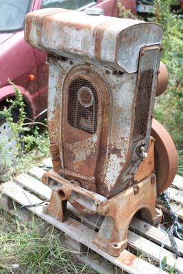 a rusted out machine sitting on a pallet next to a car