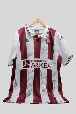 un gros plan sur un maillot de foot couvert de signatures