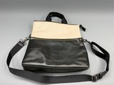 a black and white purse with a strap on a white surface
