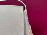 the white purse is sitting on a pink surface with a pink background