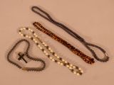 three rosary beads and a cross on a white surface