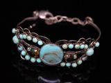 a close up of a bracelet with a turquoise stone on it
