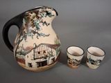 a pitcher and two cups sitting next to each other