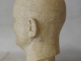 a sculpture of a man ' s head on a white surface