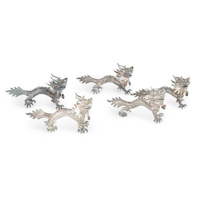trois figurines de dragons en argent sur fond blanc