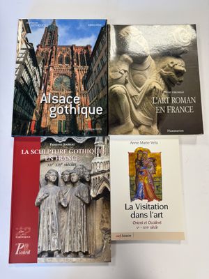 quatre livres posés sur une table recouverte d'une nappe blanche