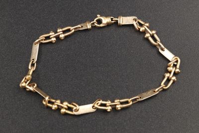 gros plan d'un bracelet en or sur une surface noire