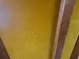 a yellow chair with a wooden seat and a yellow wall