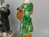 two ceramic figurines of a man and a woman in green and yellow