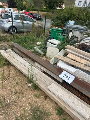 un tas de bois posé dans un jardin, près d'une clôture