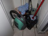 a vacuum and a bag of cleaning equipment in the corner of a room