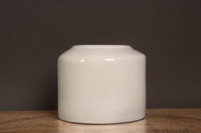 un vase blanc posé sur une table sur fond noir