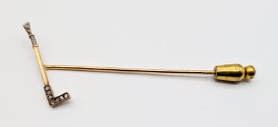 a gold pin with a key on it on a white surface