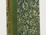 an old book with a green cover sitting on top of a white table