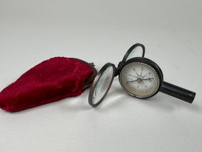 a pocket watch and a magnifying glass on a table