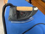 a black iron on a blue table with a cork handle