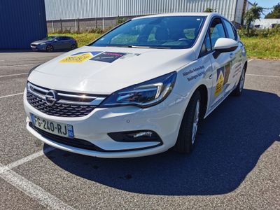 La voiture blanche est garée sur un parking, avec d'autres voitures en arrière-plan.