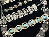 plusieurs bijoux en argent et en turquoise posés sur un fond noir