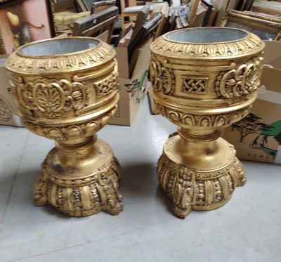 two gold vases sitting next to each other on the floor