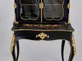une armoire peinte en noir et or, surmontée d'un miroir