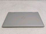 a silver laptop sitting on a white sheet on a bed