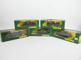 quatre boîtes contenant des trains miniatures, posées sur une surface blanche