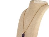 necklace with a purple stone on a gold chain on a mannequin
