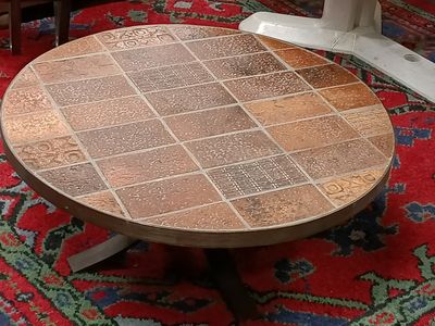 a round table with a tile top on a red rug