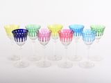 six verres à vin colorés alignés en rang sur une surface blanche