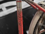a red bike parked next to a black and white car